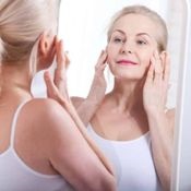 Woman touching her face in the mirror