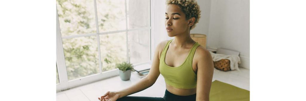 woman sitting by a window doing yoga